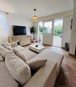 a living room with a couch and a flat screen tv at Les cigales - souplex cosy et calme in Mas-Saintes-Puelles