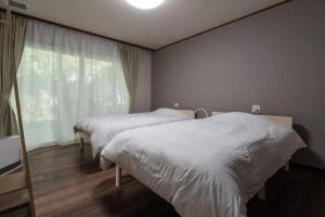 a bedroom with two beds and a large window at ペットと泊まれる一日一組限定の貸切ヴィラ　ウェルシー山中湖 in Yamanakako