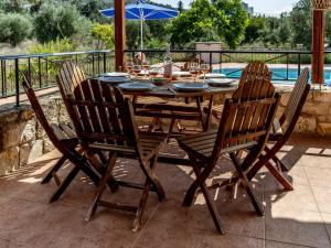 a wooden table with four chairs and a table with wine glasses at Villa Angelos with private gated pool in Almyrida