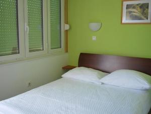 a bedroom with a bed with two pillows and two windows at Bed and Breakfast Kogoj in Nova Gorica