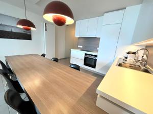 a kitchen with a wooden table and a kitchen with white cabinets at AMAZING Beach View Apartment type 28 in Ostend