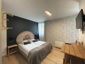 ein Schlafzimmer mit einem großen Bett und einem Holztisch in der Unterkunft Hôtel Le Bel Air in Saint-André-les-Alpes