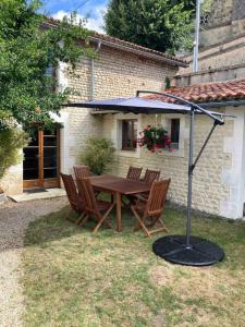 una mesa de madera y sillas con sombrilla en un patio en Stunning rural gem with pool in southwest France, en Brie-sous-Barbezieux