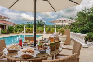 une table avec de la nourriture dessus à côté d'une piscine dans l'établissement ama Stays & Trails Palmeira De Socorro , Goa, à Vieux-Goa