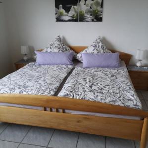 1 dormitorio con cama de madera y almohadas moradas en Ferienwohnung Prior, en Bad Emstal