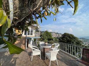 un patio con sedie bianche e un tavolo sul balcone. di Bahar Retreat And Spa , Gangtok a Gangtok