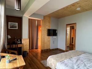 Bahar Retreat And Spa , Gangtok في جانجتوك: غرفة نوم بسرير وطاولة وتلفزيون