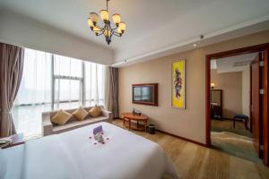 Changsha Jiaxing Inn في تشانغشا: غرفة نوم بسرير ابيض كبير واريكة