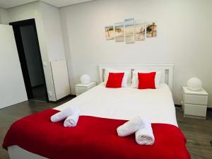 a bedroom with a large white bed with red pillows at Atlantic Surf Apartment in Ferrel
