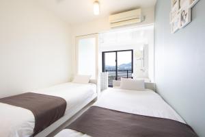 two beds in a room with a window at HOTEL E-horizon Resort コンドミニアム瀬底 in Motobu +50 photos
