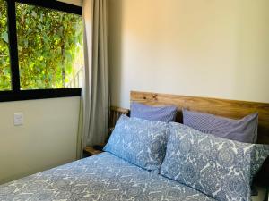 a bedroom with a bed with blue pillows and a window at Maritimus Suítes in Barretos