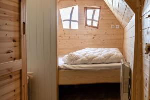 uma cama num pequeno quarto num chalé de madeira em La cabane magique em Conty