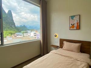 a bedroom with a bed and a large window at Pomelo Hostel in Yangshuo