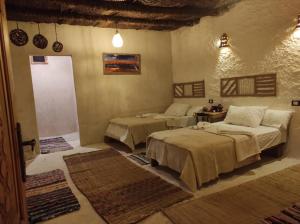 a room with two beds in a room with rugs at Eswan Hotel in Siwa
