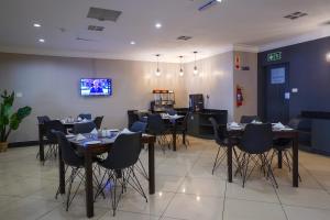 una sala da pranzo con tavoli, sedie e TV di Inani Hotel Gallagher a Midrand