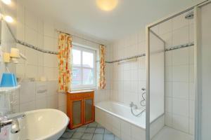 a white bathroom with a tub and a sink at Jägerstrasse 7 Ferienwohnung 8 in Kölpinsee +21 photos