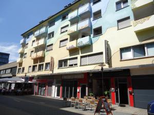 ein hohes Gebäude mit Tischen und Stühlen auf einer Straße in der Unterkunft Big Apartments in Dortmund