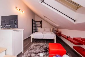Dormitorio en el ático con cama y banco rojo en Villa RICH, en Timisoara