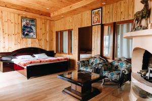 a bedroom with a bed and a couch and a table at THE HIMALAYAN WOODS, CHAUKORI in Chaukori