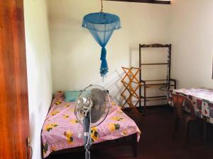 a room with a fan next to a bed at MarvelMansion hostel in Galle