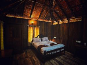 1 dormitorio con 1 cama en una habitación de madera en Mahout Resort Wayanad - An Experiential Jungle Stay with Waterfall, en Kalpetta