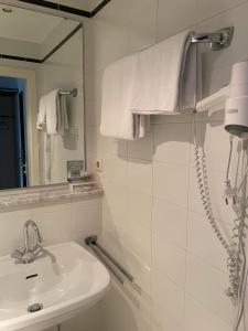 Baño blanco con lavabo y espejo en Hotel Bitterfelder Hof - Mongoo GmbH, en Bitterfeld