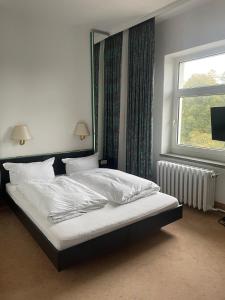 a bed in a bedroom with a large window at Hotel Bitterfelder Hof - Mongoo GmbH in Bitterfeld