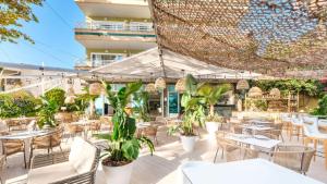 un patio al aire libre con mesas, sillas y plantas en Hotel Agua Beach "Adults only" en Palmanova