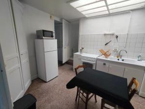 eine Küche mit einem Tisch, einer Spüle und einem Kühlschrank in der Unterkunft Maison Saujon in Saujon