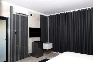 - une chambre avec des rideaux noirs, un lit et une télévision dans l'établissement The Residence Villa, à Musina