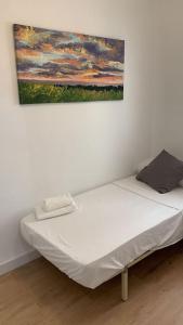uma cama num quarto com uma pintura na parede em Cozy 3bd near vibrant Valencia em Paiporta