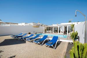 プラヤ・ブランカにあるVilla El Anclaのスイミングプールの隣の青いラウンジチェアのグループ