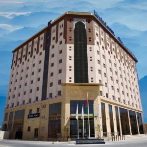 um edifício de hotel com bandeiras em frente em KYRIAD HOTEL SALALAH em Salalah