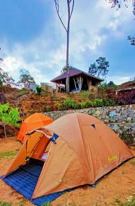 2 tende sedute per terra di fronte a un edificio di Gunung bangku ciwidey rancabali camp a Ciwidey