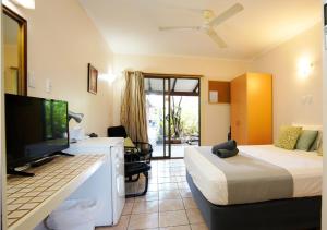 a hotel room with a bed and a tv and a desk at Kimberley Croc Motel in Kununurra +32 photos