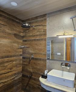 a bathroom with a sink and a wooden wall at Gulmarg Woods By Stay Pattern in Gulmarg