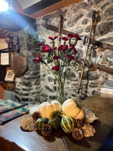 un vase avec des roses et des citrouilles sur une table dans l'établissement The Garden by LUKE, à Ezcaray