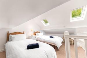 two beds in a attic bedroom with two windows at The Sheiling, Traditional Lakeland Cottage, Coniston in Coniston