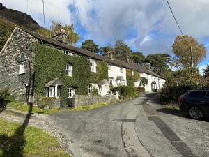 an ivycovered house with a car parked on the side of a road at The Sheiling, Traditional Lakeland Cottage, Coniston in Coniston