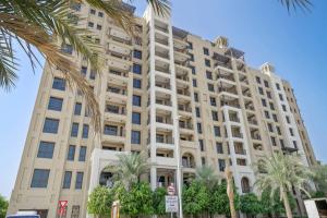 a large building with palm trees in front of it at Chic 1BR APT Rahaal 2 MJL in Dubai