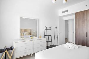 a white bedroom with a white dresser and a mirror at Chic 1BR APT Rahaal 2 MJL in Dubai