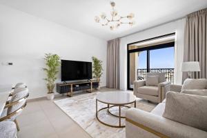 Chic 1BR APT Rahaal 2 MJL في دبي: غرفة معيشة مع أريكة وتلفزيون