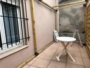una pequeña mesa blanca sentada en un patio junto a una ventana en Le COSY de Mercadet - Parking gratuit & Wifi, en Perpiñán
