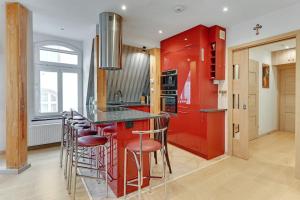 uma cozinha com armários vermelhos e um bar com bancos em Selve Sentrum by Grand Apartments em Sopot
