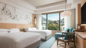 a hotel room with two beds and a table with a chair at Hong Kong Ocean Park Marriott Hotel in Hong Kong