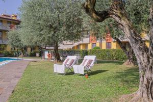 two lounge chairs sitting in the grass next to a pool at Dolce Vita Family Apartment in Sirmione