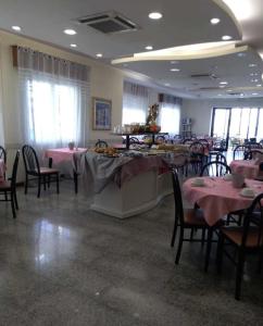 jadalnia ze stołami i krzesłami z różowymi obrusami w obiekcie Hotel Bonaria w Rimini