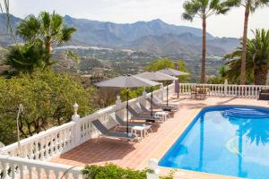 a resort pool with chairs and umbrellas and mountains at Los-Barquitos in Torrox