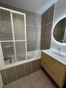 bagno con vasca, lavandino e specchio di Dahlia YourHostHelper a Caen