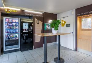 uma estação de bebidas com um vaso de plantas numa loja em B&B HOTEL Bordeaux Sud em Villenave-dʼOrnon